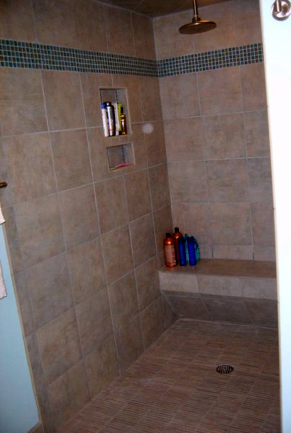 Walk-in tile shower with a built-in bench, niches and a rain head