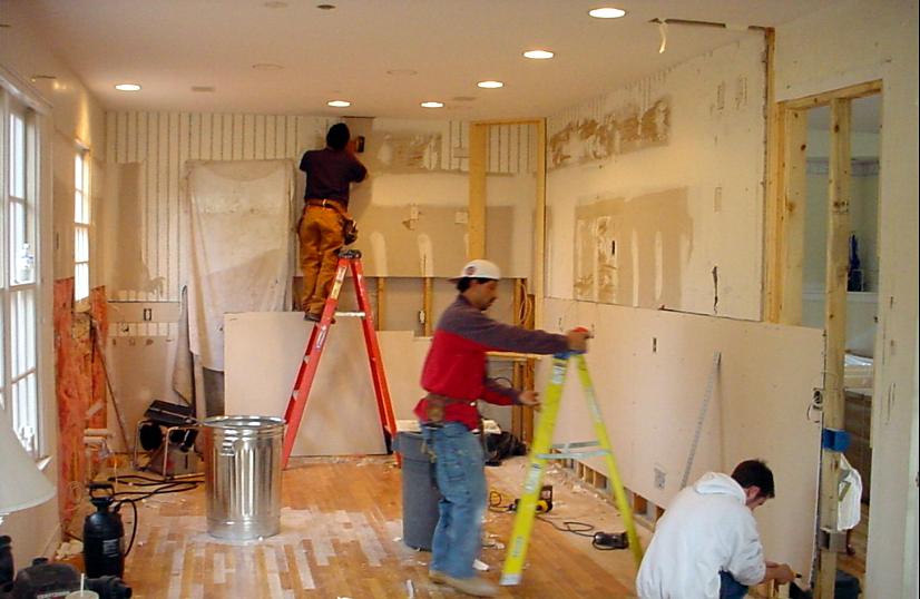 Three carpenters hanging drywall and framing during a kitchen renovation