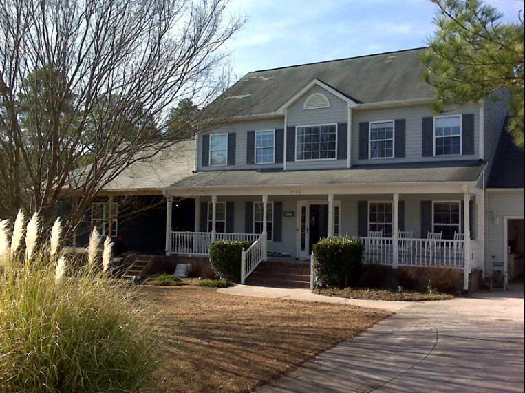 Two-story home with a new in-law suite wing and a long front porch