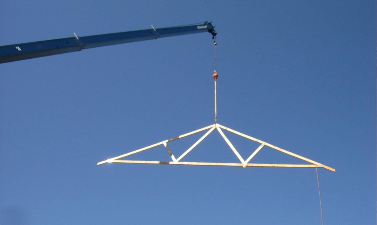 A roof truss lifted into place by crane