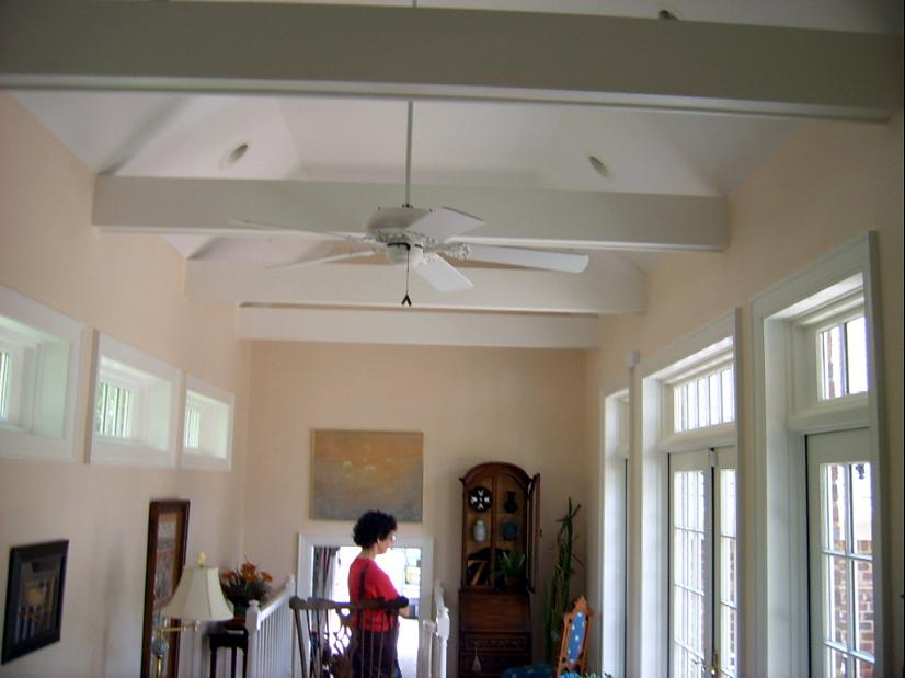 Bright sunroom addition with painted beams, transom windows and a ceiling fan